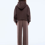 Person wearing a brown hoodie and pants on a white background