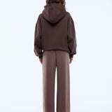 Person wearing a brown hoodie and pants on a white background
