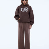 Person wearing a brown 'Pelly Studio' hoodie and pants on a white background