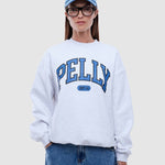 Person wearing a white sweatshirt with 'PELLY' branding, blue jeans, and a blue cap on a light gray background