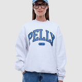 Person wearing a white sweatshirt with 'PELLY' branding, blue jeans, and a blue cap on a light gray background