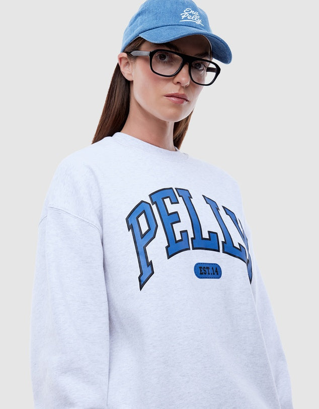 Person wearing a white sweatshirt with 'PELLY' branding and a blue cap.