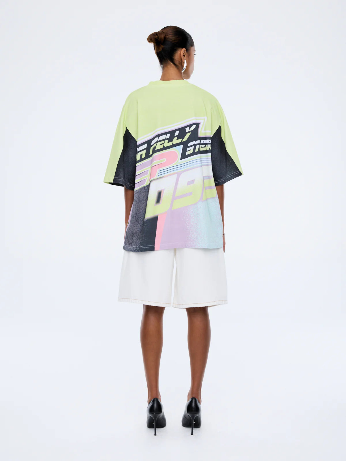 Person wearing a colorful graphic t-shirt and white shorts on a white background