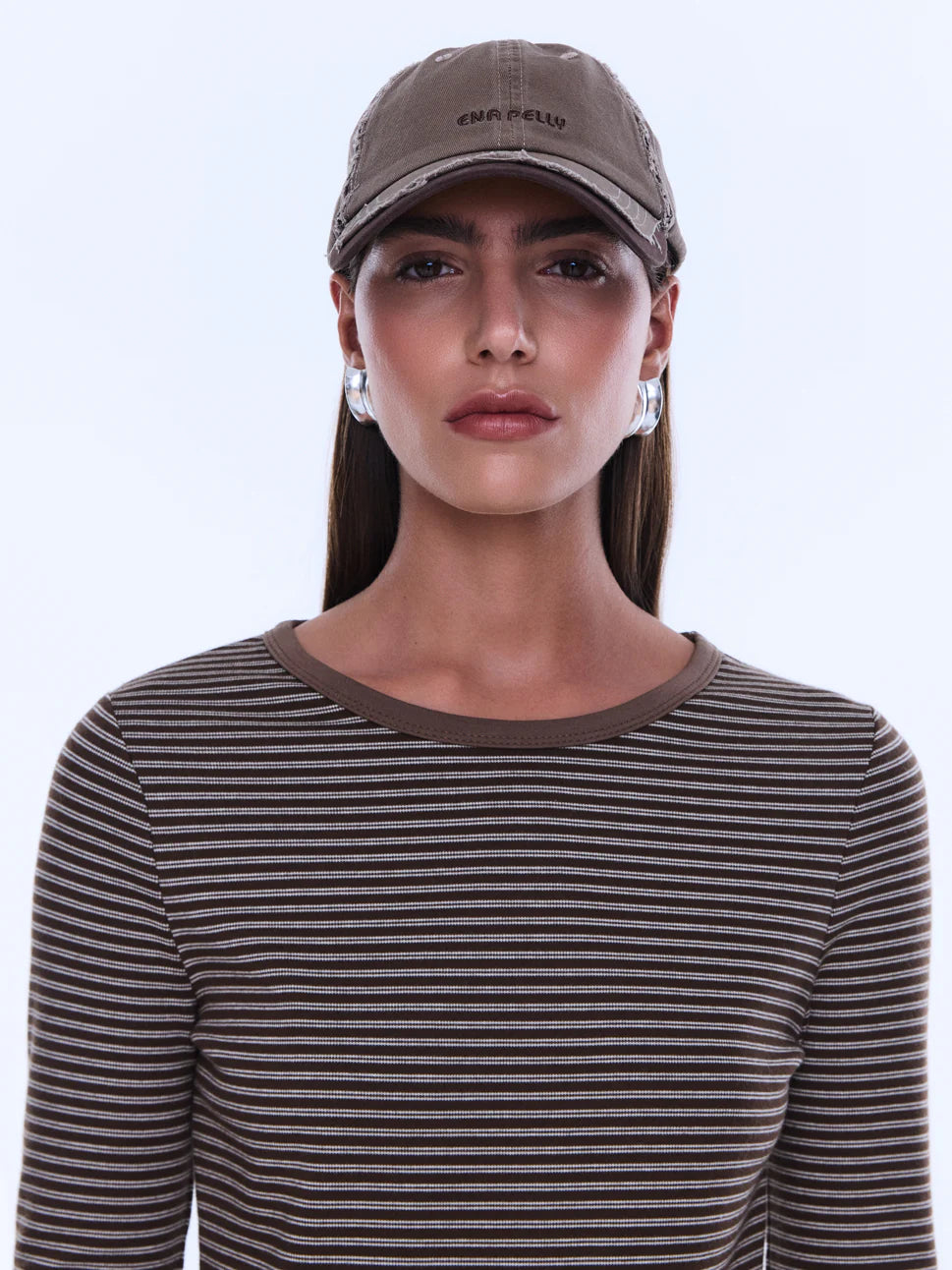Woman wearing a brown cap and striped shirt against a white background