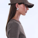 Woman wearing a brown baseball cap and striped shirt on a light gray background