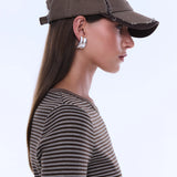 Woman wearing a brown baseball cap and striped shirt on a light gray background