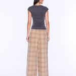 A woman shown from the back wearing a dark gray short-sleeve top and beige plaid wide-leg pants against a plain white studio background.