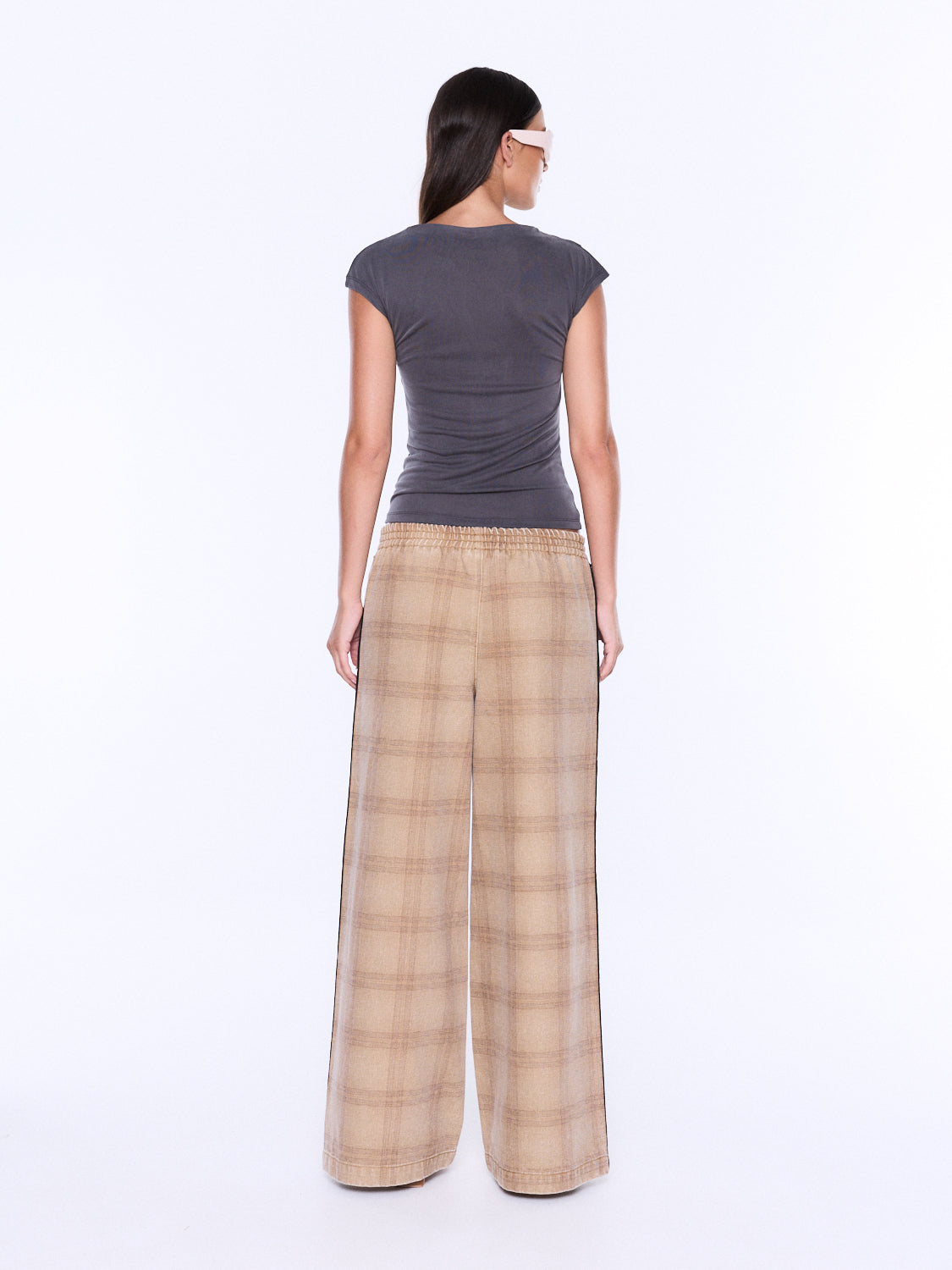 A woman shown from the back wearing a dark gray short-sleeve top and beige plaid wide-leg pants against a plain white studio background.