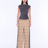 A model stands against a plain white studio background wearing a dark gray sleeveless top and beige plaid wide-leg pants with black side stripes.