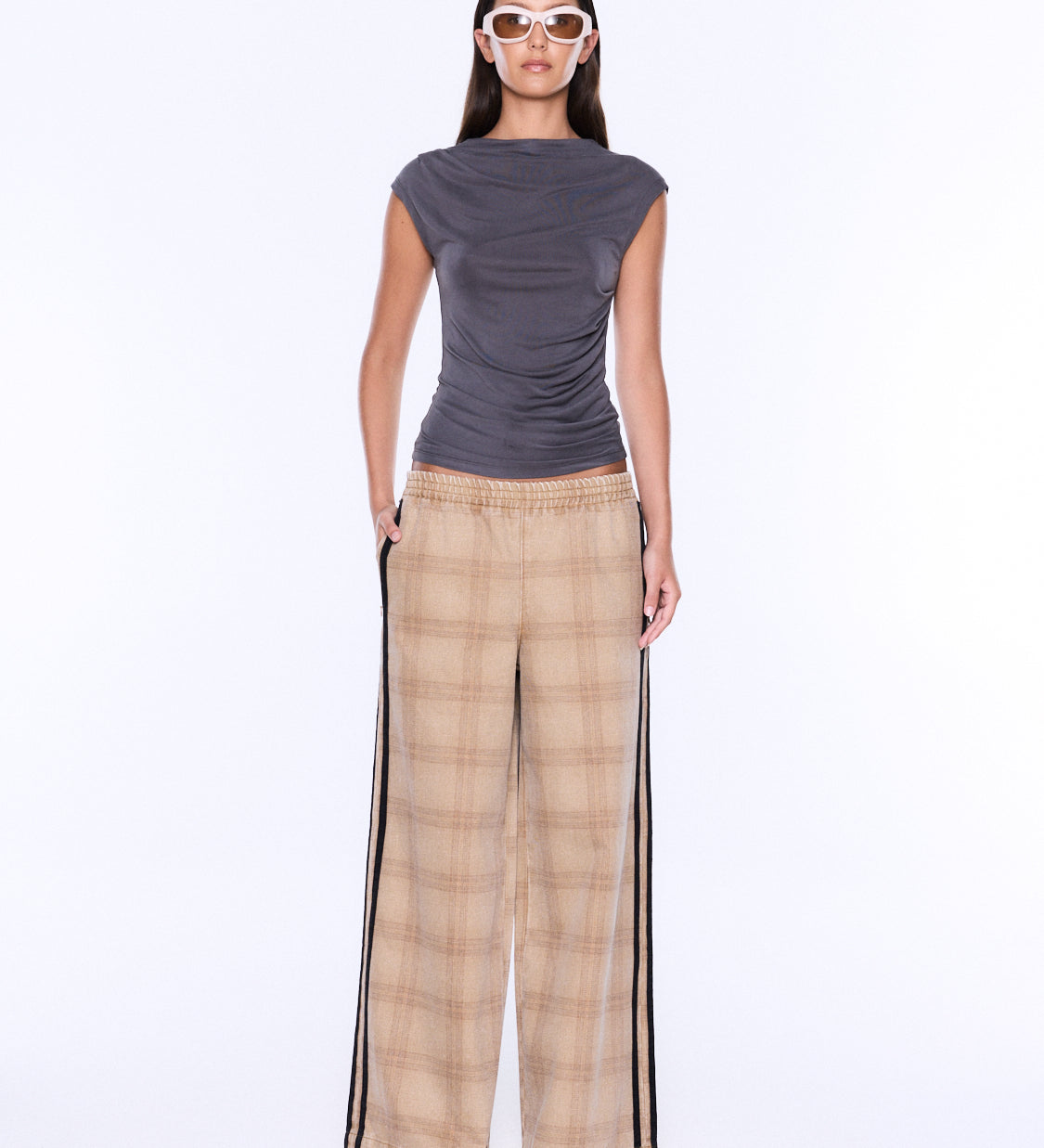 A model is shown from the back wearing a dark gray sleeveless top and beige plaid wide-leg pants with black side stripes, set against a plain white studio background.