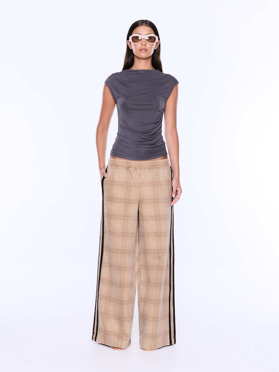 A model is shown from the back wearing a dark gray sleeveless top and beige plaid wide-leg pants with black side stripes, set against a plain white studio background.