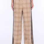 A person wearing wide-leg plaid pants in beige and brown with black side stripes, paired with a dark gray top and tan sandals, shown against a plain white studio background.