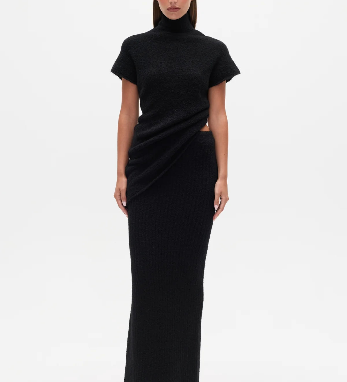 Woman wearing a black Top with a high neckline  and a long black skirt on a white background