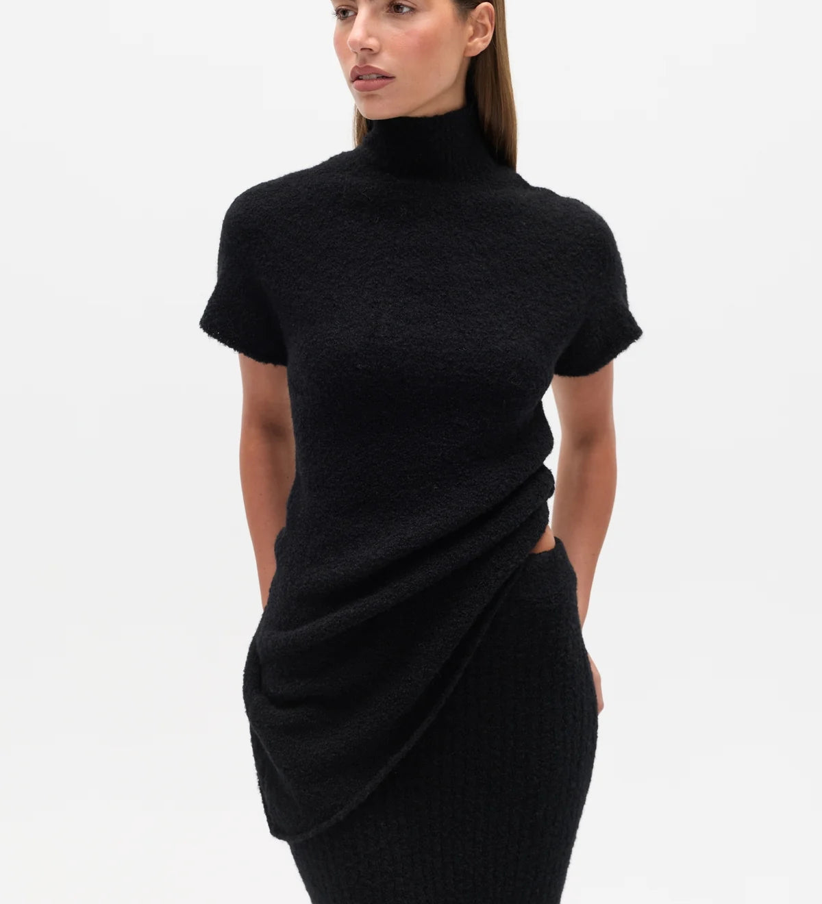 Woman wearing a black Top with a high neckline  and a long black skirt on a white background