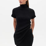 Woman wearing a black Top with a high neckline  and a long black skirt on a white background