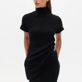 Woman wearing a black Top with a high neckline  and a long black skirt on a white background