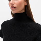 Woman wearing a black High neck top against a white background