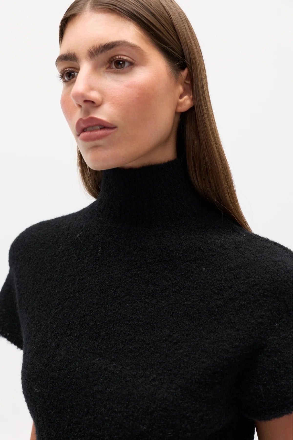 Woman wearing a black High neck top against a white background
