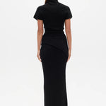 Woman wearing a black Top with a high neckline  and a long black skirt on a white background