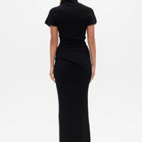 Woman wearing a black Top with a high neckline  and a long black skirt on a white background