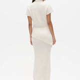Woman wearing a white high neck top and long white skirt on a white background