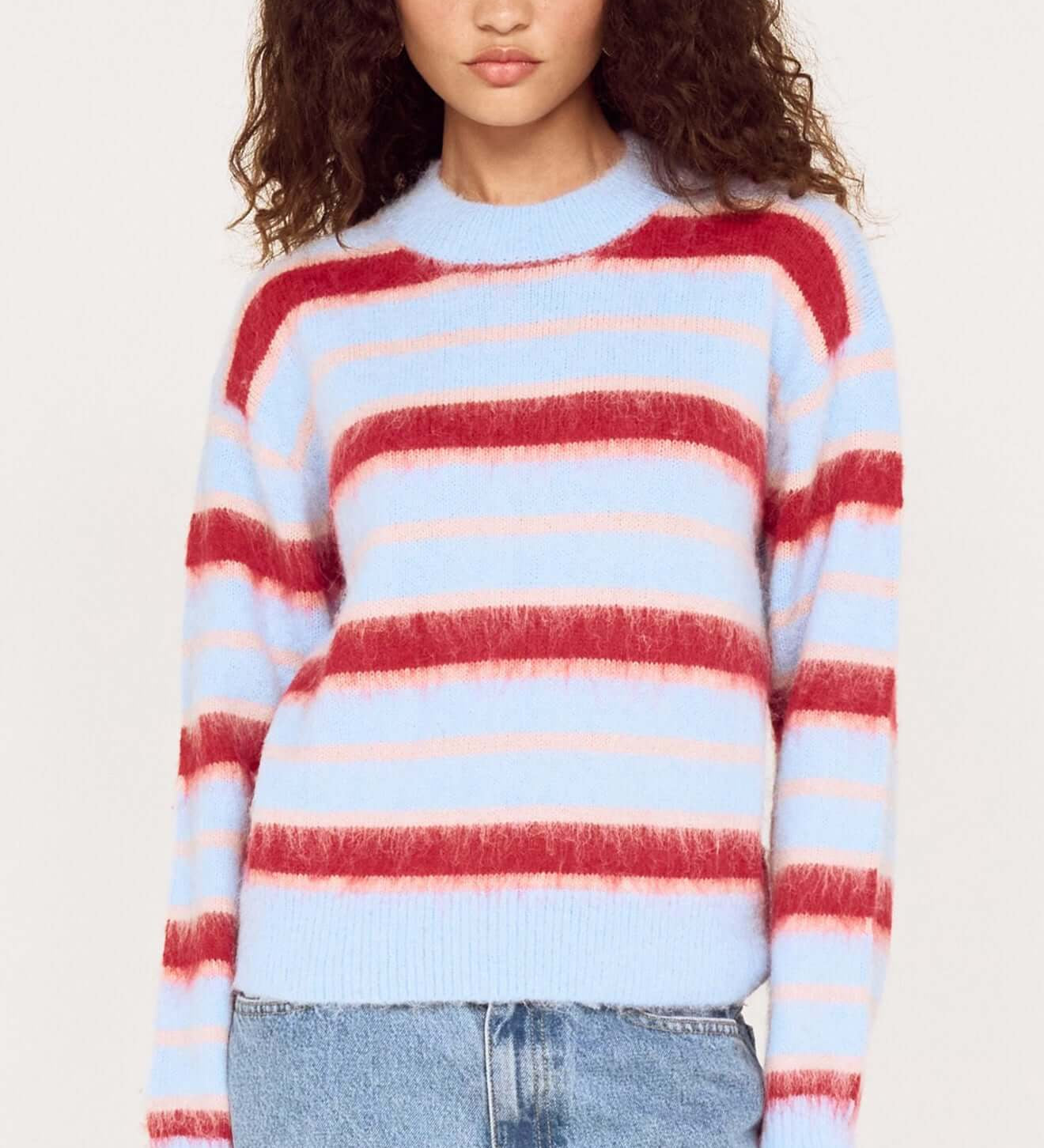 Woman wearing a multicolored striped sweater and jeans on a white background