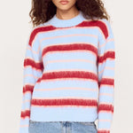 Woman wearing a multicolored striped sweater and jeans on a white background