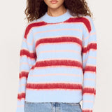 Woman wearing a multicolored striped sweater and jeans on a white background