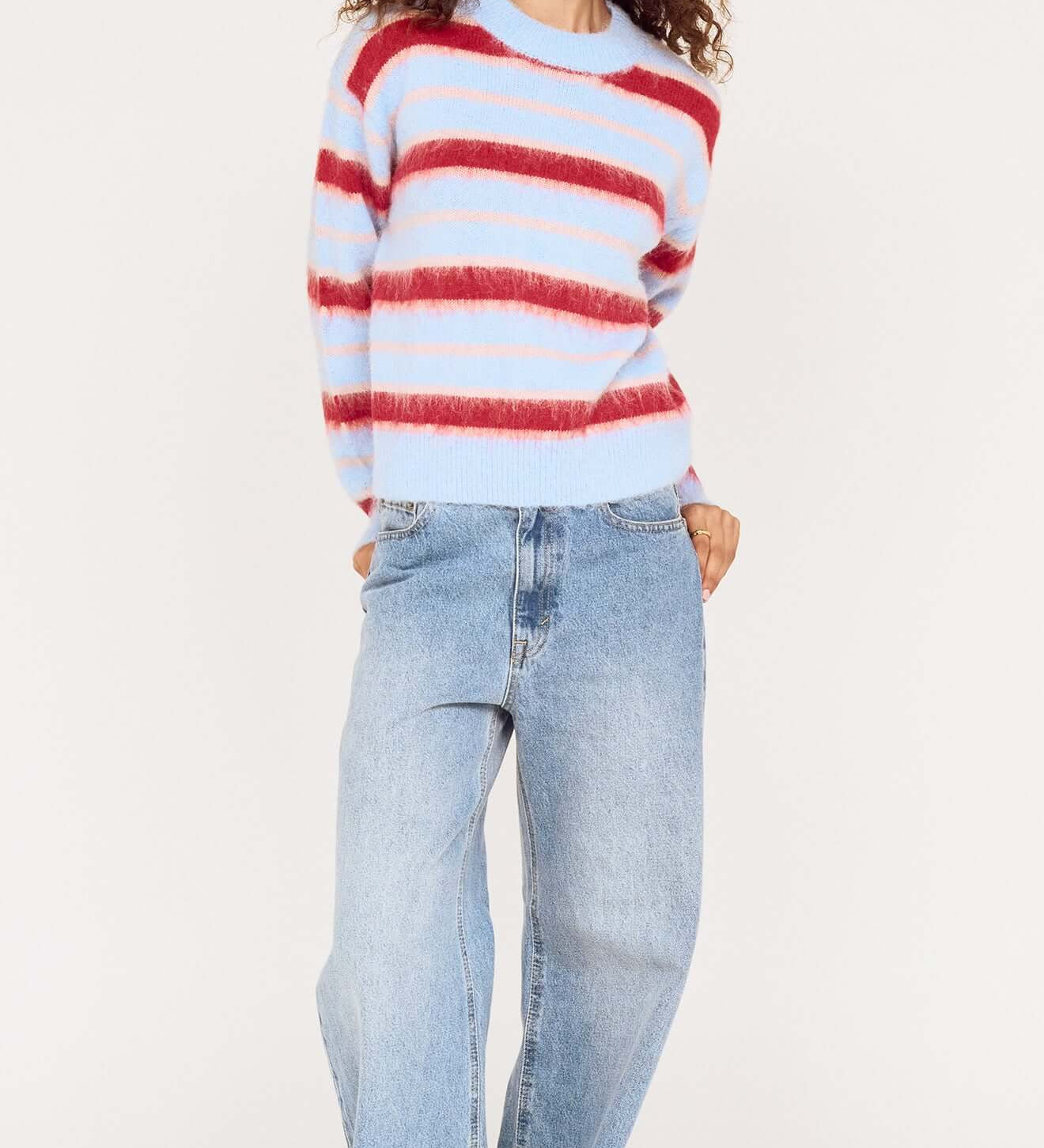Person wearing a red and white striped sweater and blue jeans on a white background
