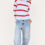 Person wearing a red and white striped sweater and blue jeans on a white background