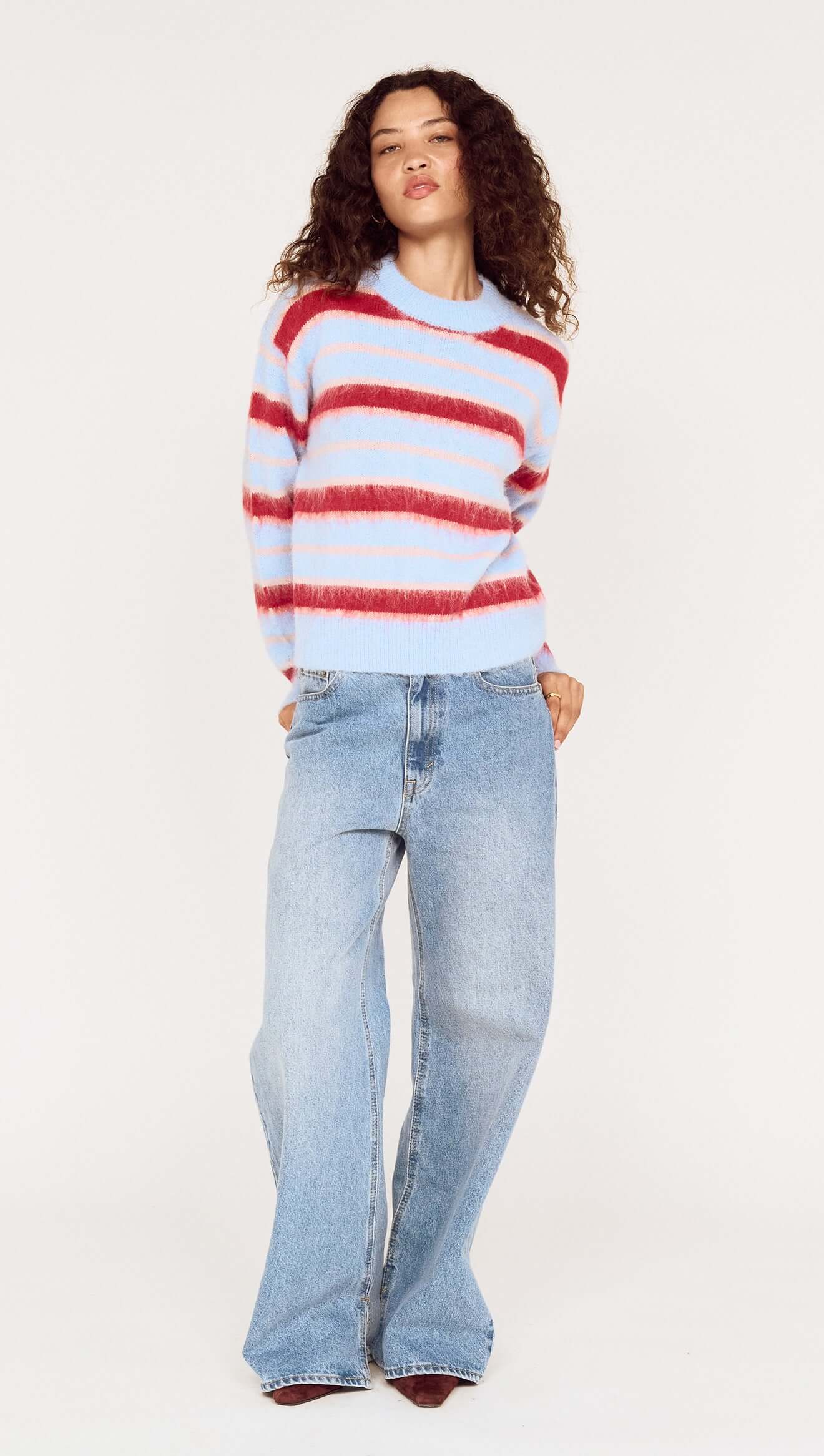Person wearing a red and white striped sweater and blue jeans on a white background