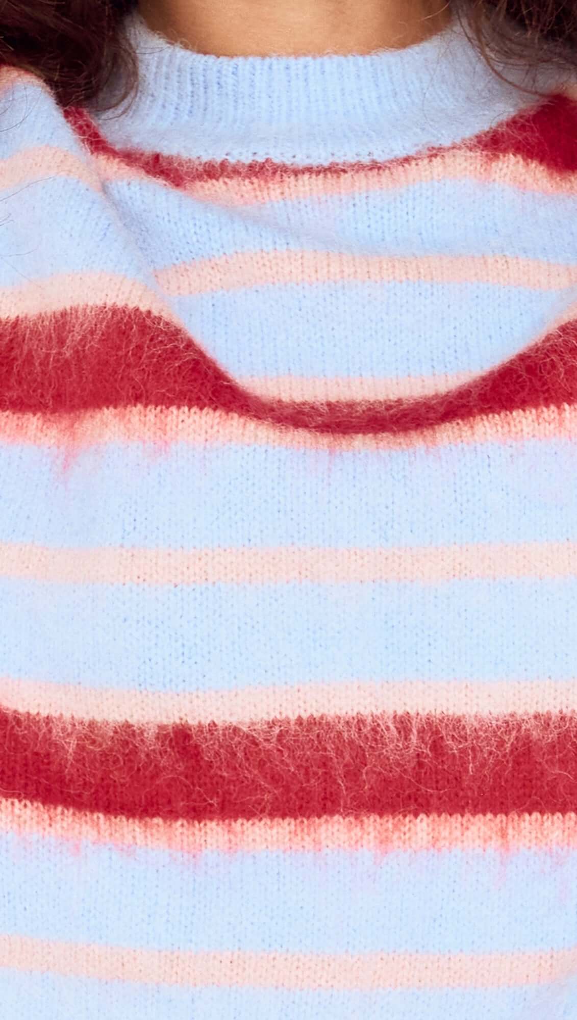 Close-up of a sweater with red, pink, and light blue stripes.