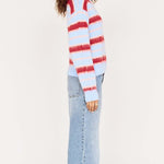 Person wearing a red and white striped sweater and light blue jeans on a white background