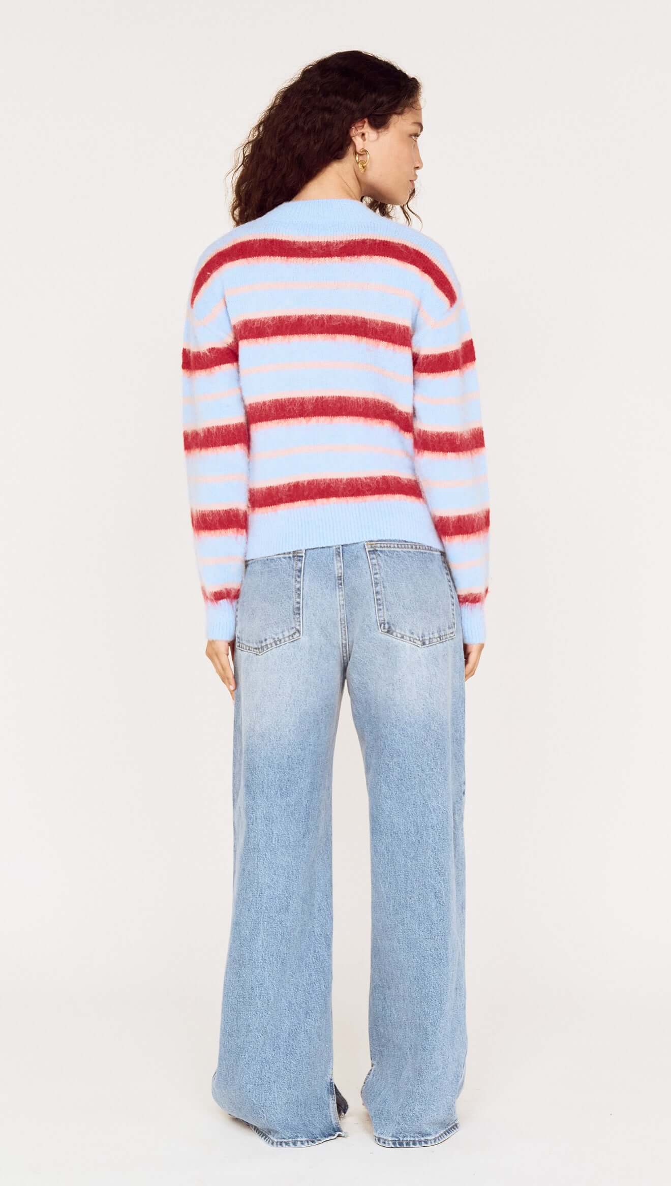 Person wearing a red and blue striped sweater and light blue jeans on a white background