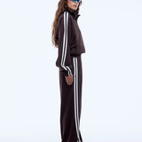 Person wearing a black tracksuit with white stripes on a white background