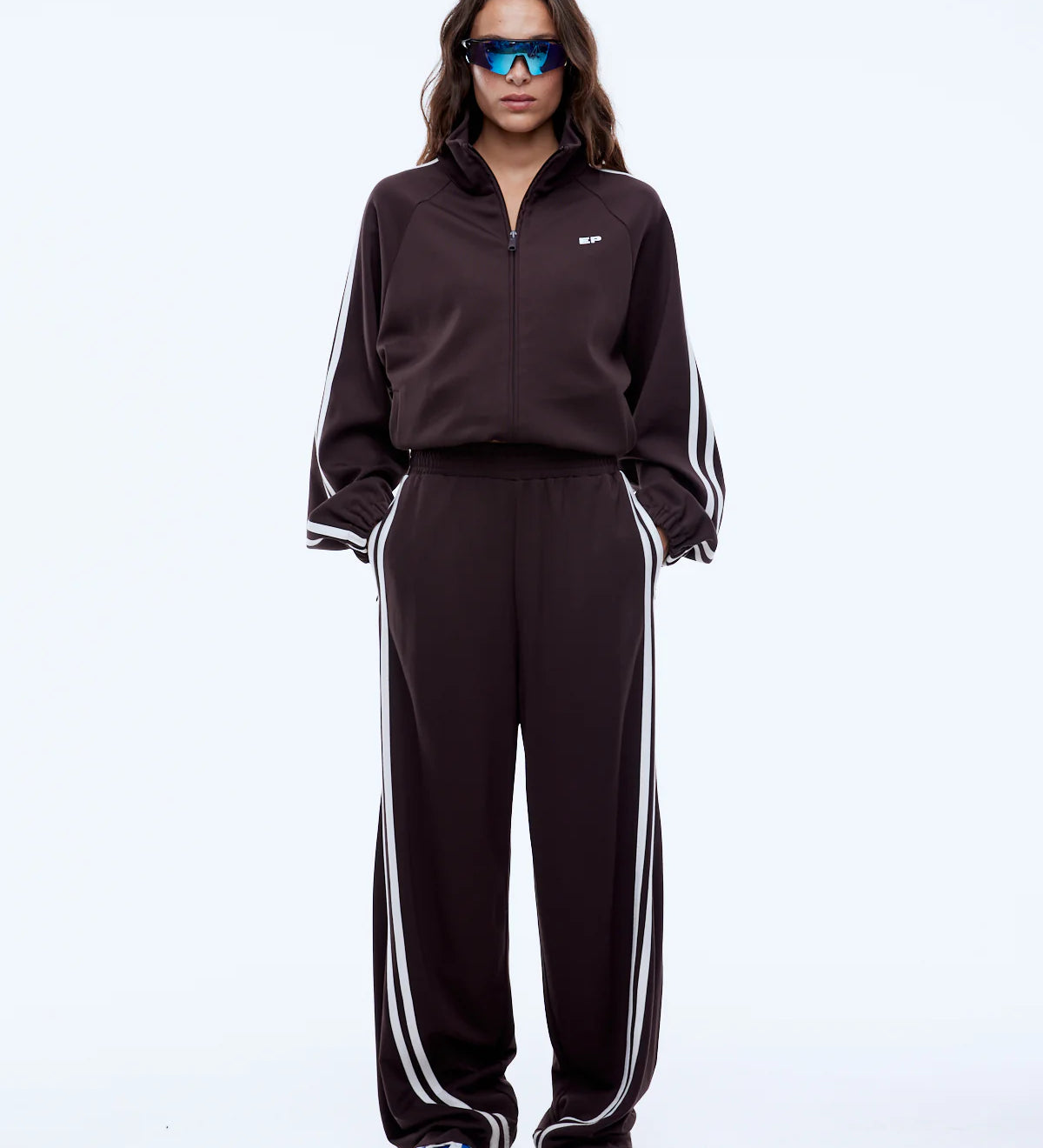 Person wearing a black tracksuit with white stripes on a white background
