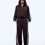 Person wearing a black tracksuit with white stripes on a white background