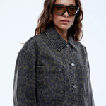 Woman wearing a patterned coat and sunglasses on a white background