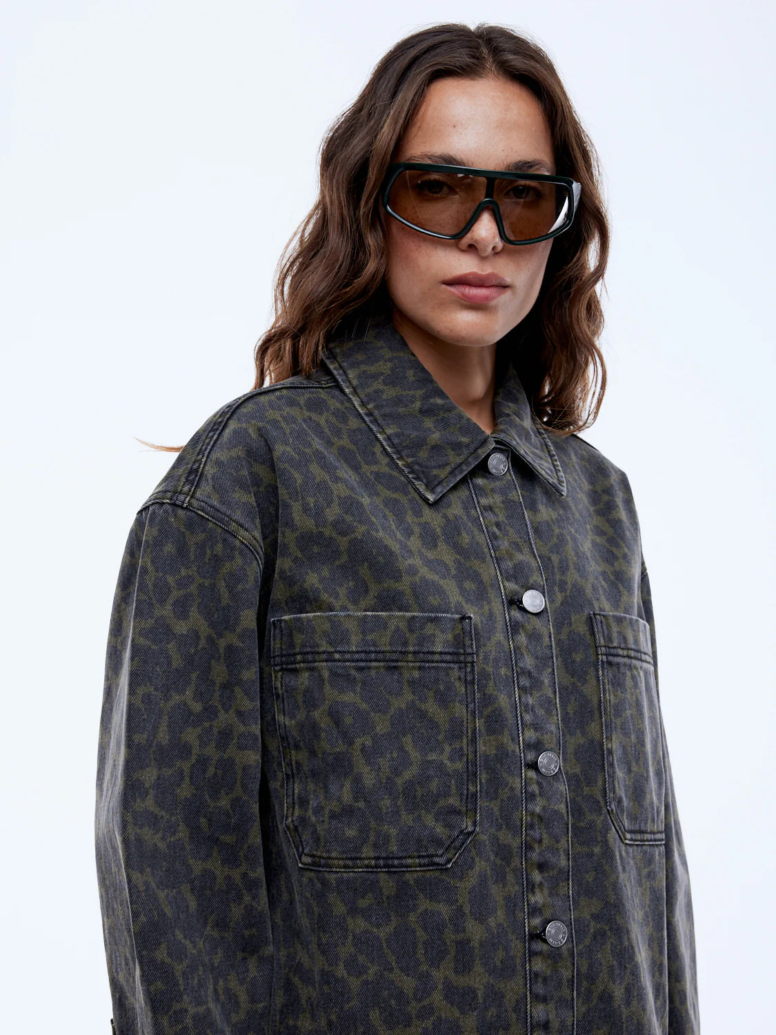 Woman wearing a patterned coat and sunglasses on a white background