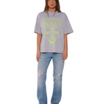 Person wearing a gray t-shirt with text and blue jeans on a white background