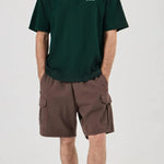 Person wearing a green t-shirt and brown cargo shorts on a white background