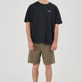 Man wearing a black t-shirt with a logo and olive shorts on a white background