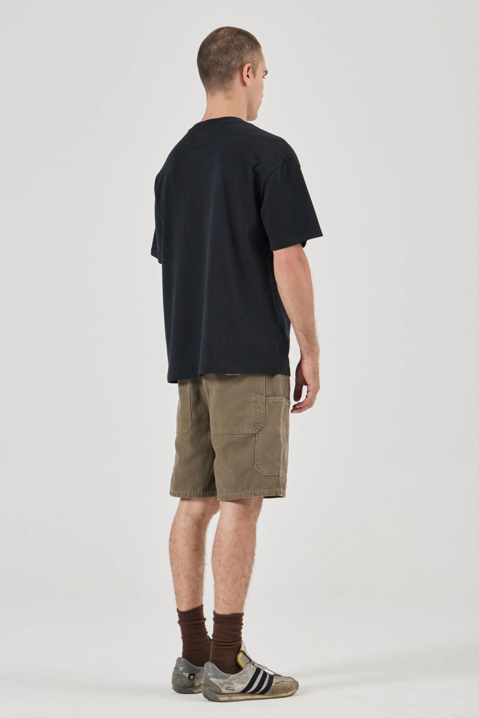 Man wearing a black t-shirt and olive shorts on a white background