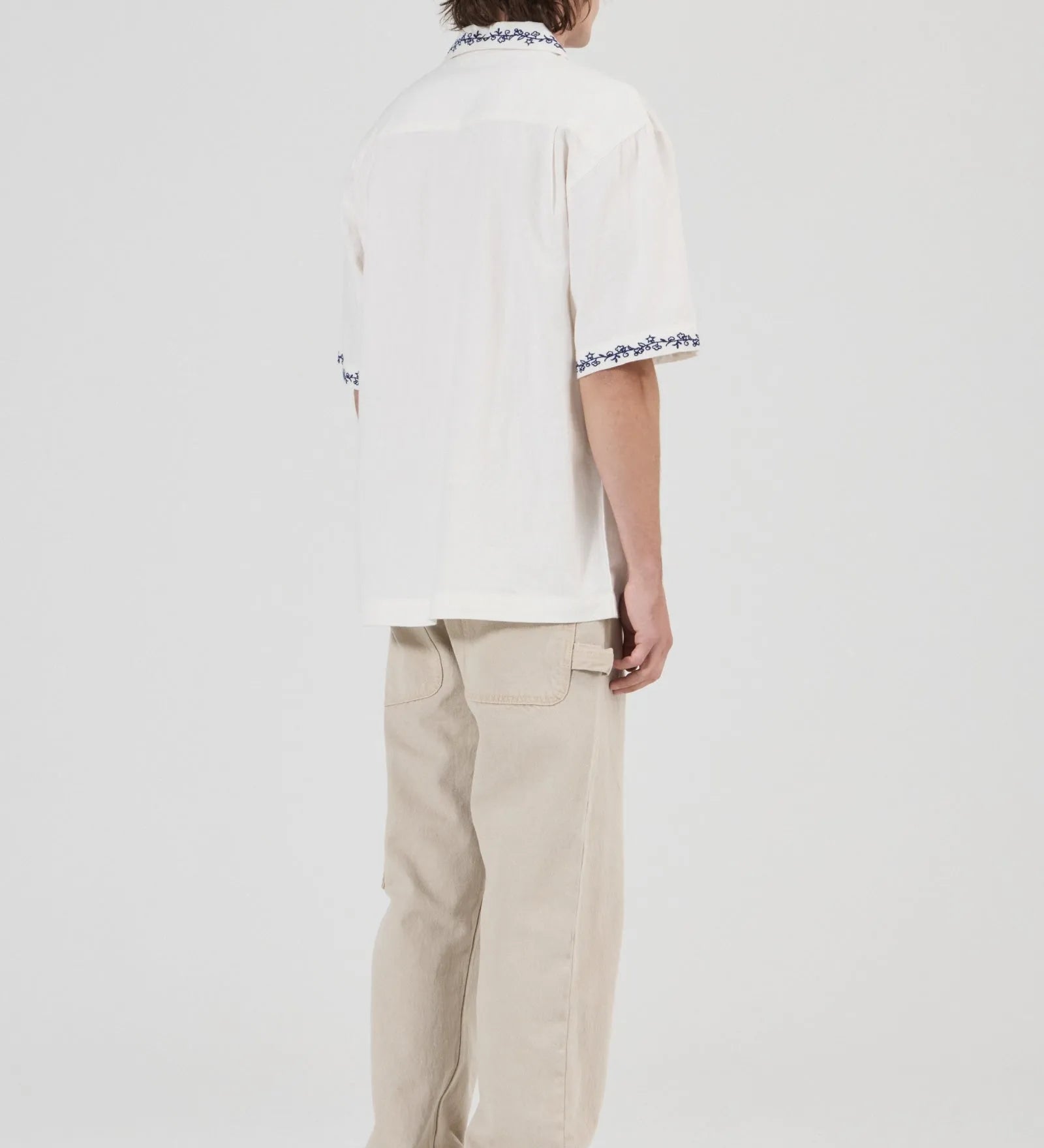 Person wearing a white shirt with text and beige pants on a white background