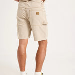 A person shown from the back wearing light beige cargo shorts, a matching beige top, white socks, and gray sneakers against a plain white studio background.