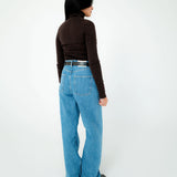 Person wearing blue jeans and a brown top on a white background