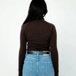 Person wearing a brown long-sleeve top and blue jeans from behind on a white background
