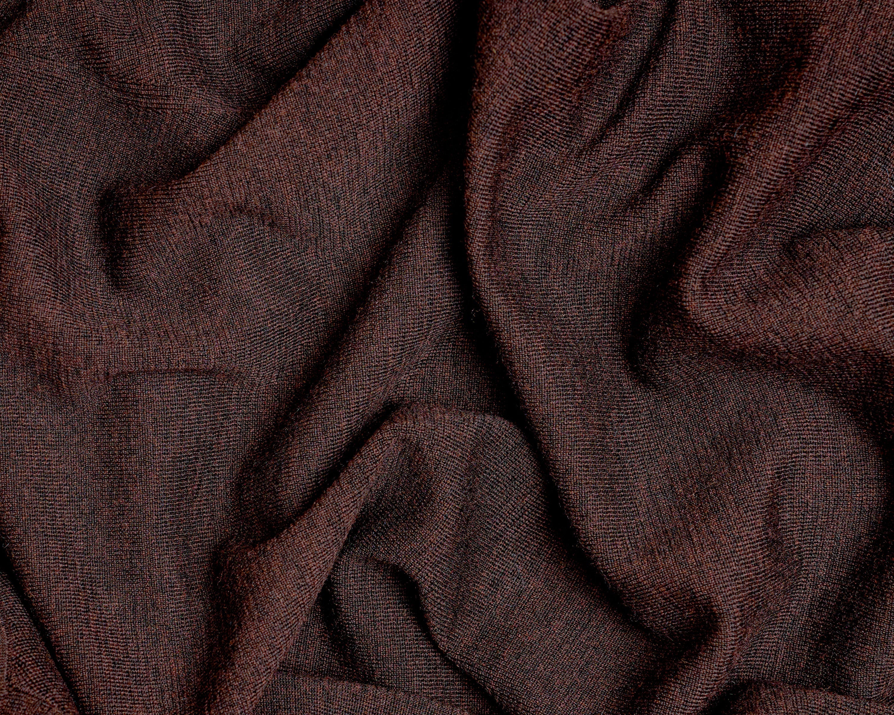 A close-up of draped dark brown fabric with a soft, textured weave and subtle sheen.