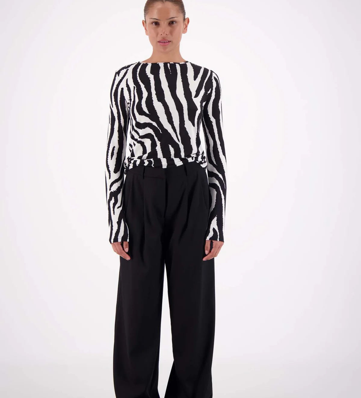Person wearing a zebra-striped sweater and black pants on a white background