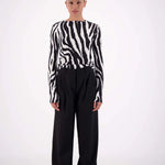 Person wearing a zebra-striped sweater and black pants on a white background